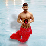 The December Diamonds January Birthstone-Garnet Merman features a muscular torso, red shimmering tail, and gold belt, holding a large garnet gemstone while emerging from blue water.