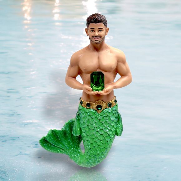 The December Diamonds May Birthstone-Emerald Merman features a hand-painted figurine with a green glittery tail, jeweled belt, and a large emerald gemstone, making it a perfect ornament for May birthdays.