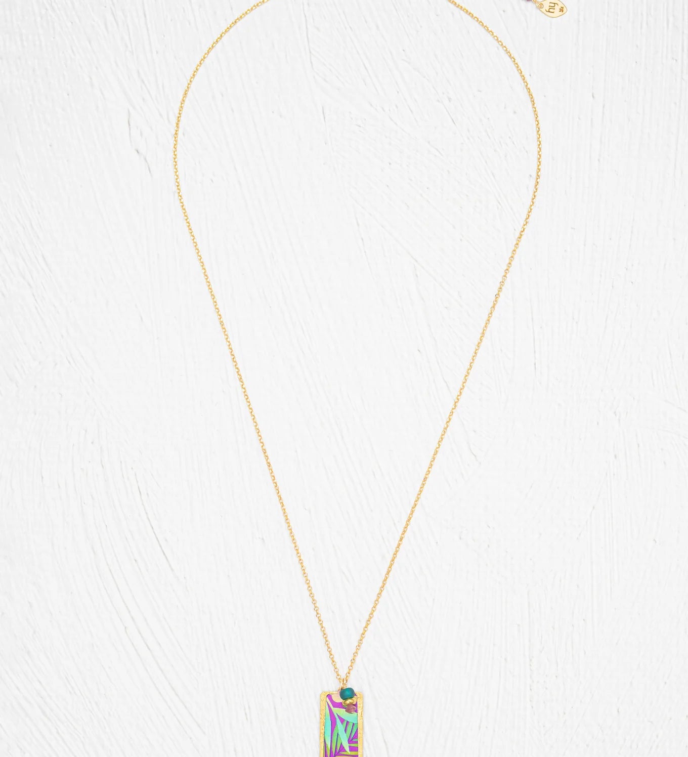 Davy Rectangle Two Layers Tropic Magenta Necklace by Holly Yashi features a rectangular pendant with an abstract, multicolored geometric design. This hand-painted piece stands out beautifully against a white, textured background.