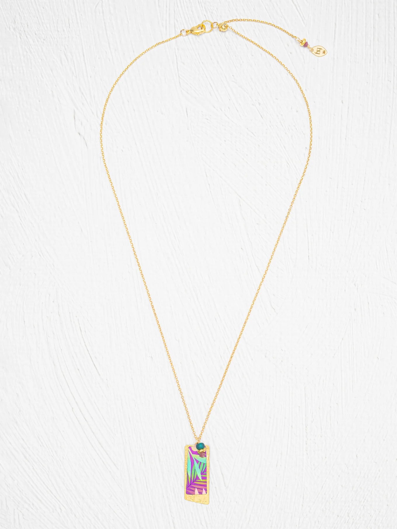 Davy Rectangle Two Layers Tropic Magenta Necklace by Holly Yashi features a rectangular pendant with an abstract, multicolored geometric design. This hand-painted piece stands out beautifully against a white, textured background.