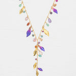 The Holly Yashi Calliope Tropic Punch Necklace showcases a gold-plated chain with gold leaves, colorful beads, and purple enamel niobium leaves in a V-shape on a white background.