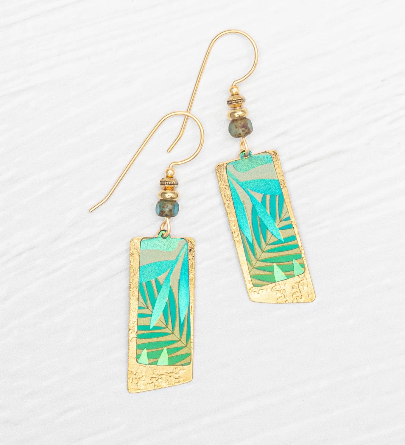 Introducing the Holly Yashi Davy Rectangles Two Layers - Tropic Green Earrings: hand-painted gold earrings featuring layered rectangular shapes with abstract green and teal geometric designs. Each earring is accented with a delicate beaded detail above the rectangles and finished with gold hooks, beautifully displayed on a white textured background. These striking accessories are perfect for any occasion.