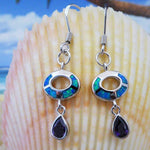 Jewelry Network's Caribbean Opal Oval w/Amethyst Teardrop Dangle Earrings are shown before a large seashell, with a beach scene in the background.