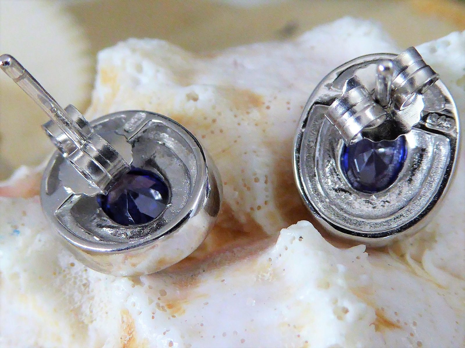 Close-up of Jewelry Network’s Caribbean Opal 4 Segments/Oval Amethyst CZ Post Earrings, featuring oval amethyst cubic zirconia stones, displayed against a textured white and beige shell background.