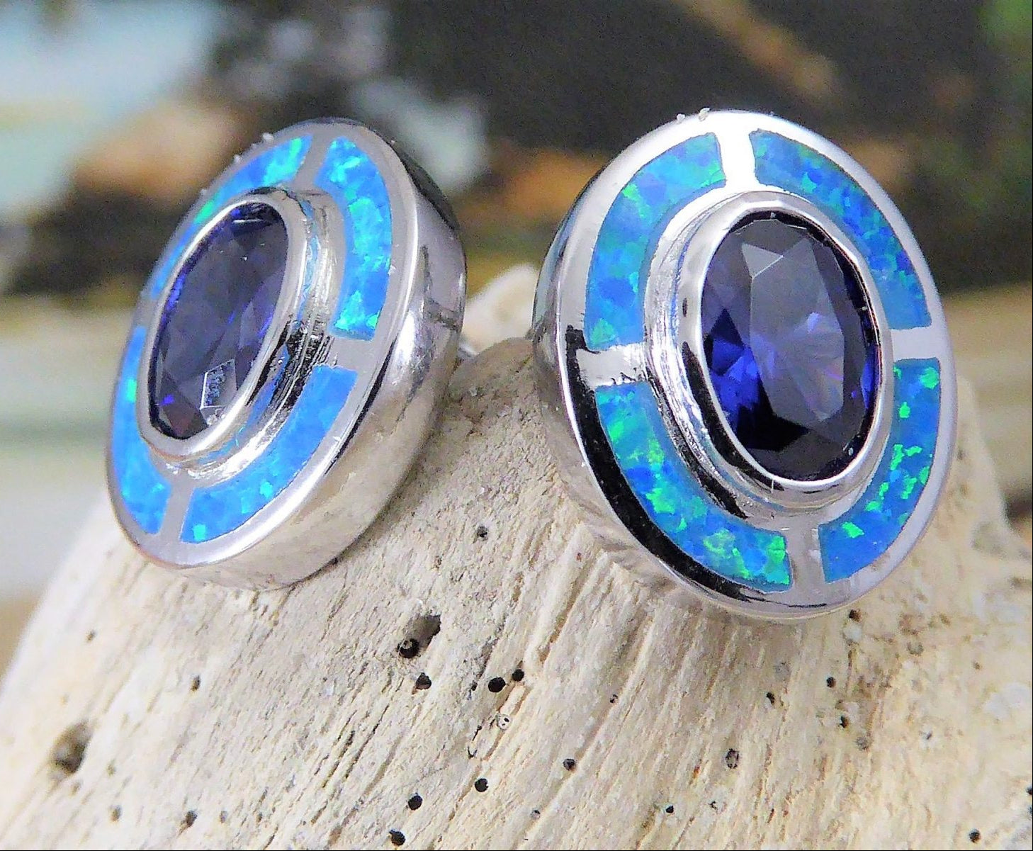 Close-up of Jewelry Network’s Caribbean Opal 4 Segments/Oval Amethyst CZ Post Earrings, featuring oval amethyst cz centers bordered by bright blue-green opal inlay, shown on a light stone background.