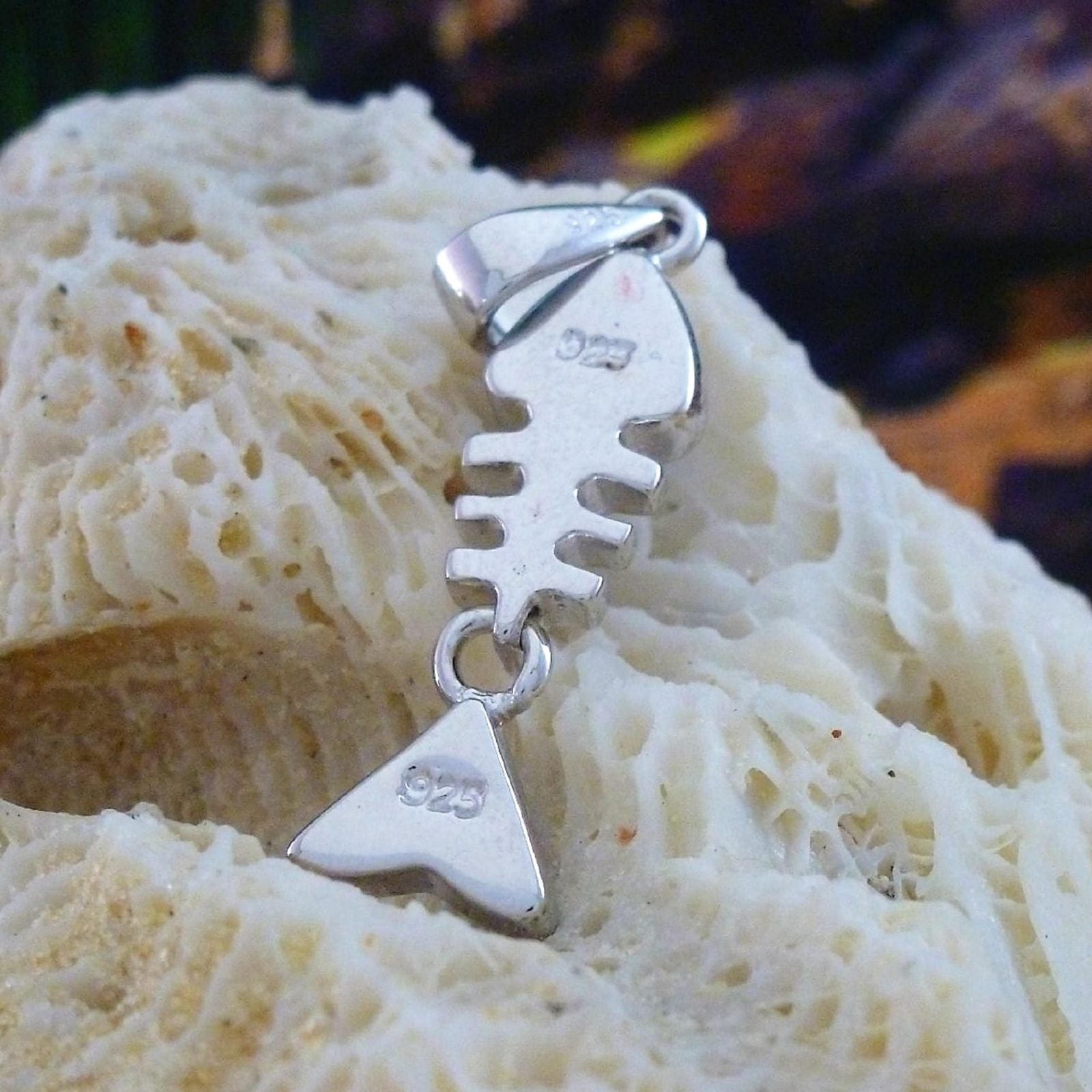 The Caribbean Opal Fish Bones-Pendant ONLY by Jewelry Network sits on a textured cream coral rock, its sterling silver marked 925, with a blurred dark background.