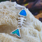 The Jewelry Network's Caribbean Opal Fish Bones-Pendant ONLY features a sterling silver fishbone design with geometric shapes, intricate details, and shimmering blue-green opal inlays, displayed on a textured cream surface.