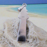 The Caribbean Opal Lighthouse-Pendant ONLY by Jewelry Network, crafted in sterling silver and marked 925, rests on textured white coral with a sandy beach and blue ocean blurred in the background—a striking nautical accessory.