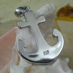 The Caribbean Opal Anchor w/ Segments-Pendant ONLY by Jewelry Network, a shiny silver 925 Sterling Silver anchor engraved with "925," sits on a white seashell with sand and a blurred yellow object in the background.