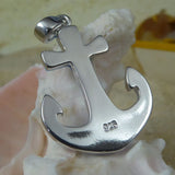 The Caribbean Opal Anchor w/ Segments-Pendant ONLY by Jewelry Network, a shiny silver 925 Sterling Silver anchor engraved with "925," sits on a white seashell with sand and a blurred yellow object in the background.