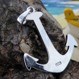 The Jewelry Network Caribbean Opal Anchor-Pendant ONLY, crafted in 925 Sterling Silver, is displayed on textured driftwood with a blurred beach and yellow boat in the background.