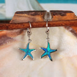 Jewelry Network's Caribbean Opal Starfish Dangle Earrings feature 925 Sterling Silver with rhodium plating, blue and green synthetic opal centers, and hook backs, displayed against a large seashell.