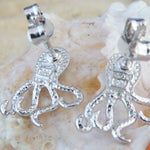 The Caribbean Opal Octopus Post Earrings by Jewelry Network, crafted from 925 Sterling Silver with textured detailing, are displayed on a light-colored seashell background.