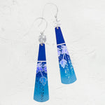 The Midnight Blue Tula Earrings by Holly Yashi Jewelry feature a blue gradient with silver hooks and floral designs. Adorned with decorative dots, theyre hypo-allergenic and set against a textured surface, enhanced by elegant 18k gold-filled accents.