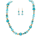 Introducing the A-Train Gold Blue Mixed Glass Bead Necklace Set—a dazzling set featuring a beaded blue and gold necklace with coordinating blue and gold beaded drop earrings, beautifully showcased on a white background. This elegant Glass Bead Necklace Set adds a vibrant touch of color to any ensemble.