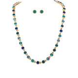 A-Train Gold Round Blue Multicolor Crystal Links Necklace Set features a gold necklace adorned with round blue, teal, and clear crystals, paired with matching blue stud earrings. Displayed on a white background, this elegant set is perfect for adding a touch of sophistication to any ensemble.
