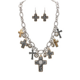 Introducing the A-Train Two Tone Oxidized Swirl and Scroll Cross Charms Necklace Set, featuring a silver chain adorned with intricately designed cross charms in gold and silver finishes. The set includes matching cross earrings with striking black and white details, blending classic elegance with contemporary style reminiscent of oxidized swirl jewelry.