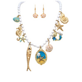 A-Train's Gold Faux Pearl Seaside Sardines Charm Necklace Set, featuring ocean-themed charms and matching gold earrings, is displayed on a white background.
