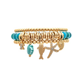 Introducing the A-Train Gold Blue Ceramic Shell Sea Charms Bracelet—an elegant piece adorned with gold and turquoise ceramic beads and featuring sea-themed charms such as a shell, fish, starfish, and a turquoise accent. Perfect for any sea charms bracelet collection.