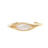 Introducing the Gold White Wire Wrapped Crystal Cuff (Moonstone) Bracelet by A-Train—a stunning adjustable cuff featuring a central moonstone, delicately wire-wrapped in gold for an elegant eye-shaped design. This versatile accessory effortlessly elevates any ensemble for any occasion.
