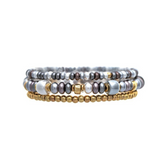The A-Train Metal Look Beads Three Piece Bracelet Set features layered bracelets adorned with metallic gold, silver, and dark gray metal look beads, stacked together on a white background for a striking mixed-metal inspired accessory.