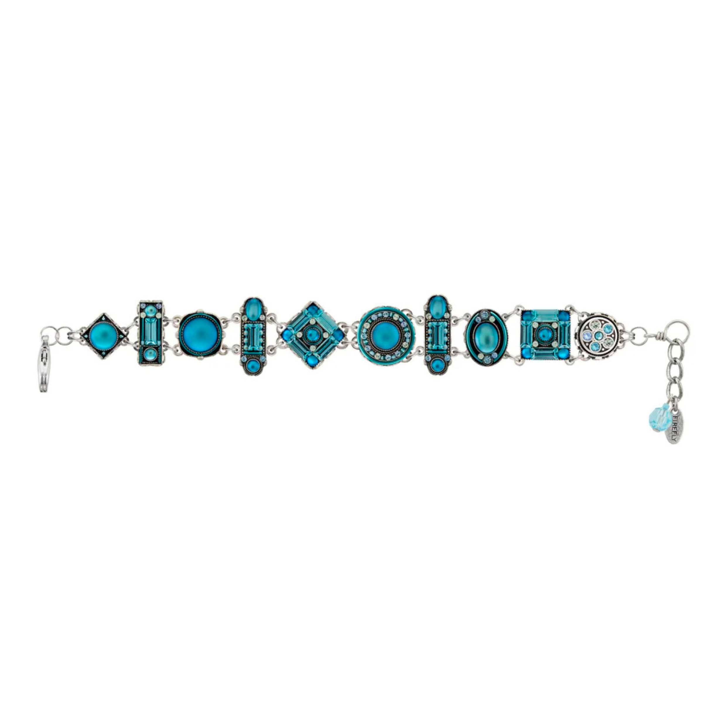 Introducing the La Dolce Vita Light Blue Bracelet by Firefly Jewelry—a stunning handmade piece featuring alternating geometric shapes adorned with blue and turquoise stones and intricate designs, all linked together by delicate silver connectors. Two small blue charms dangle from the clasp on the right end, making this Fair Trade accessory from Firefly a uniquely beautiful addition to your jewelry collection.