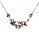 The Scalloped Multi-Color Flower Necklace from Firefly features a silver chain adorned with vibrant pink, blue, and yellow flowers alongside green leaves, all intricately arranged in decorative floral and leaf patterns. This stunning piece highlights Firefly’s signature artisanal craftsmanship.