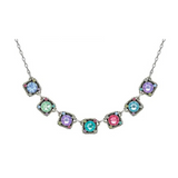 Introducing the Firefly Rainbow Small Squares Multi-Color Necklace: a delicate silver necklace featuring eight square, multicolored gemstone pendants, each bordered by tiny colored stones and artfully arranged in a gentle curve along the chain. This handmade piece by Firefly Jewelry is crafted with care to highlight vibrant hues and timeless elegance.