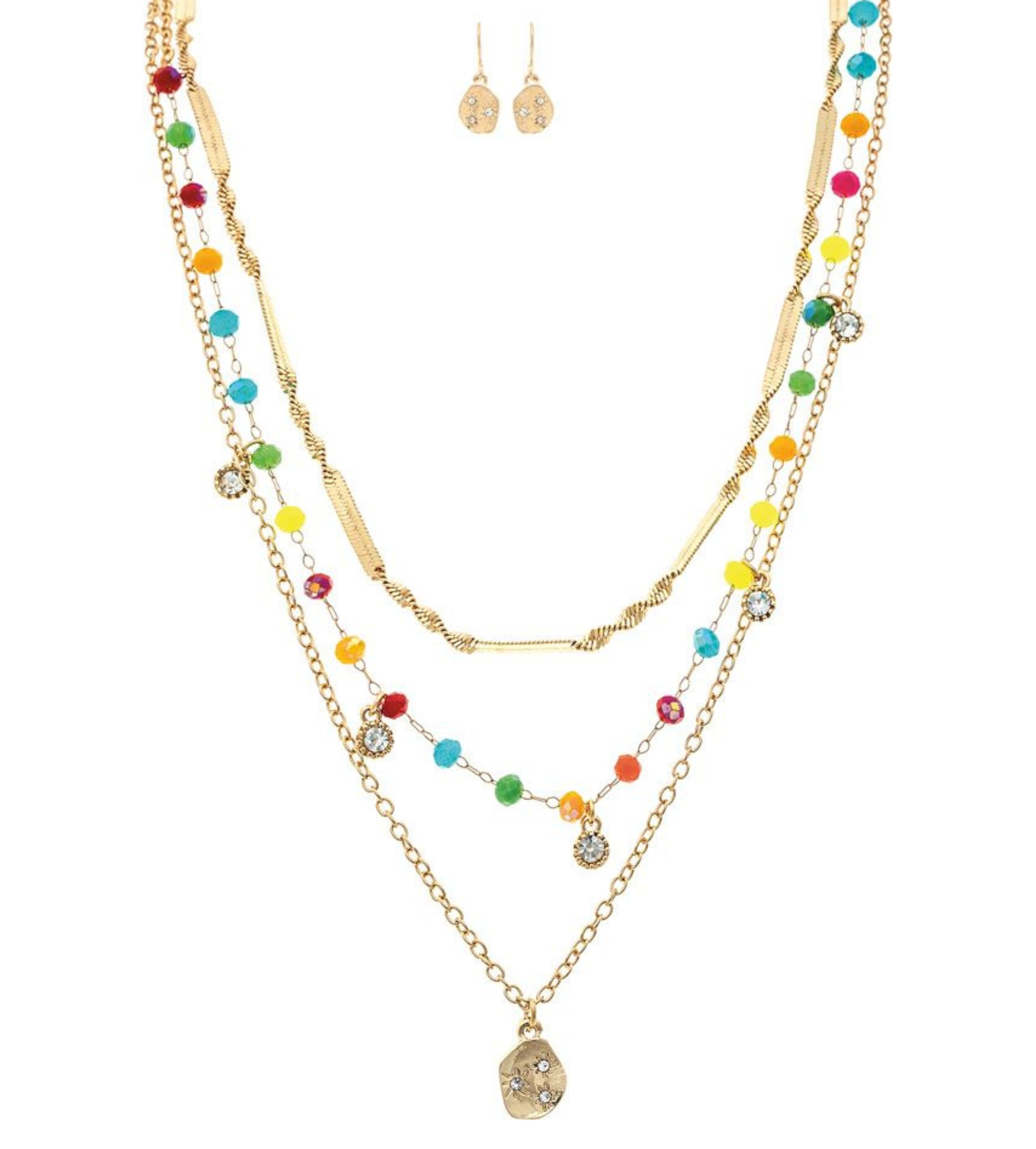 The A-Train Gold Multi-Color Fancy Chain Layer Necklace Set includes layered gold necklaces with colorful beads and sparkling pendants, paired with matching earrings featuring small gold skull charms.