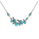 The Moonlight Scallop Necklace Light Blue by Firefly is a fair-trade piece crafted from silver and adorned with light blue gemstones in an intricate floral and leaf motif. This handmade Firefly necklace showcases small and medium blue stones paired with silver leaves on a fine chain, elegantly displayed on a white background.