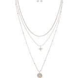 The A-Train Silver Layered Celestial Necklace Set features layered silver chains with starburst and round star pendants, complemented by matching stud earrings.