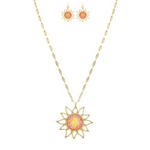 The A-Train Gold Pink/Orange Druzy Sun Necklace Set features a sun-shaped pendant and matching earrings with intricate pink and orange centers, all crafted from mixed jeweler’s metals on a delicate, elongated chain.