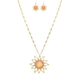 The A-Train Gold Pink/Orange Druzy Sun Necklace Set features a sun-shaped pendant and matching earrings with intricate pink and orange centers, all crafted from mixed jeweler’s metals on a delicate, elongated chain.