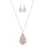 The A-Train Silver Cry Stripe Teardrop Necklace Set includes a long, textured pendant necklace with sparkling crystals and matching hammered teardrop dangle earrings.