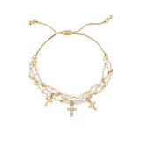 The A-Train Gold Faux Pearl Bead Cross Charm Bracelet features three cross charms and double strands of small white pearls, offering an adjustable fit and timeless style to enhance any outfit.