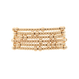 The A-Train Gold Mixed Ball Bead 6 Piece Set Bracelet features multiple rows of small, round gold beads in a stacked design, creating an elegant look against a white background.