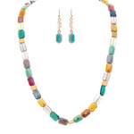 The A-Train Gold Multi Fire Polish Faceted Beads Necklace Set showcases vibrant cube and faceted beads in multiple colors, paired with matching dangle earrings featuring turquoise blue beads and gold hooks, all crafted from premium mixed jeweler’s metals.