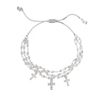 The A-Train Silver Faux Pearl Bead Cross Charm Bracelet features layered chains, three cross pendants, and faux pearl beads for an elegant look.