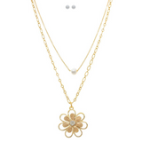 The A-Train Gold Freshwater Pearl Flower Blossom Layer Necklace Set includes a gold chain with a pearl accent, a gem-centered flower blossom necklace, and two small round stud earrings.