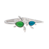 The A-Train Silver Blue/Green Hinged Turtle Bangle Bracelet features two stylish turtles—one with a green teardrop shell, the other with blue—on a white background, adding an elegant touch to any outfit.