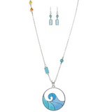 The A-Train Silver Blue Inlay Wave Necklace Set includes a silver necklace with a circular ocean wave pendant and matching earrings with turquoise and blue-green beads, plus colorful charms on one side of the mixed-metal chain.
