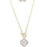 The A-Train Gold/White Shell Clover Front Toggle Necklace Set features a gold chain with a front toggle clasp, a white four-leaf clover pendant with central gem, and matching clover stud earrings.
