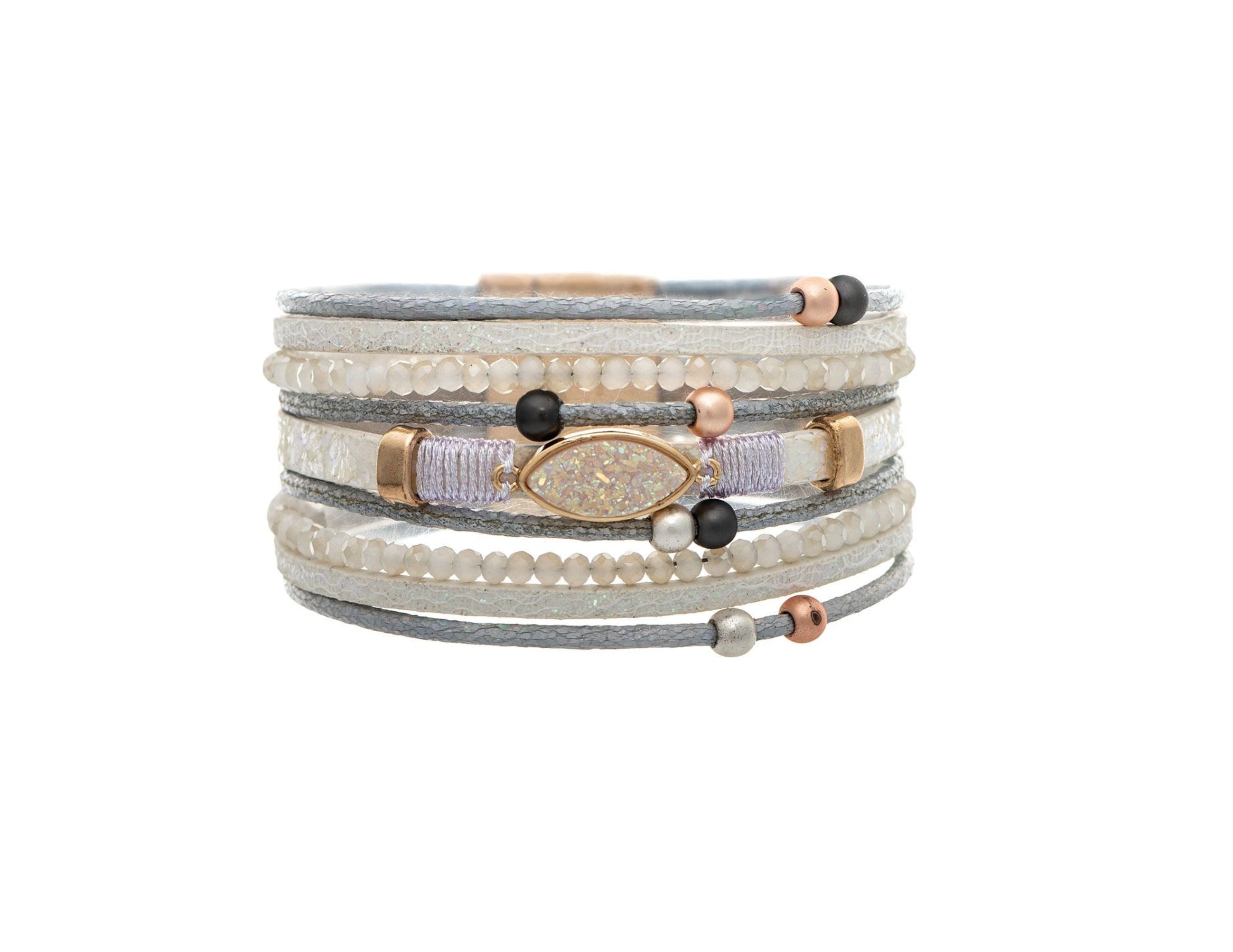 The A-Train Gold White Druzy Cord Magnetic Bracelet pairs gray cord, small white beads, black and rose gold accents, and a central oval opalescent stone for a stylish, multi-layered look.