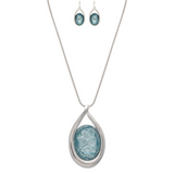The A-Train Silver Big Blue Crystal Necklace Set features a high-quality silver chain with a large blue textured oval pendant and matching blue oval drop earrings—ideal for special occasions.