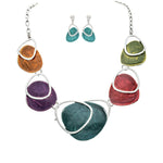 The A-Train Silver Multi Paint Palette Necklace Set features a silver chain with vibrant, irregular pendants crafted from quality mixed metals, plus coordinating teal dangle earrings with silver accents.