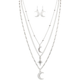 The A-Train Silver Moons & Star Layer Necklace Set includes four layered necklaces with crescent moon and star pendants, crafted from mixed jeweler’s metals, plus matching silver crescent moon dangle earrings.