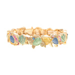 The A-Train Gold Multi-Color Turtles and Shells Beach Bracelet features jeweled blue, green, and pink accents on high-quality metal turtles, linked in a continuous design and shown on a white background.