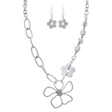 The A-Train Silver Flower Chain Link Necklace Set includes a necklace and dangle earrings with large chain links, a wire-style flower pendant, and a textured flower charm, all crafted from mixed jeweler’s metals.