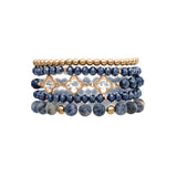 The A-Train Gold Mix Bead Sodalite Clovers 5 Pc Set Bracelet features five flexible bracelets with alternating gold and dark blue beads, including faceted blue beads and gold quatrefoil accents.