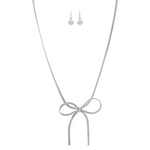 The A-Train Silver Herringbone Chain Bow Tie Necklace Set features a silver bow pendant and matching drop earrings with round beads, elegantly displayed on a white background.